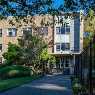 A modern architectural building surrounded by lush greenery and a well-maintained pathway.