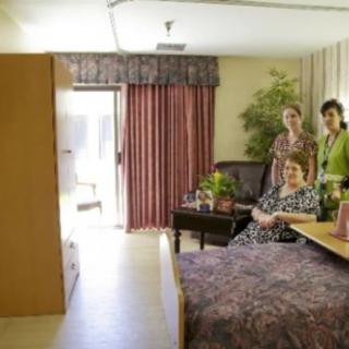 Three people sitting in a well-furnished room with a large window and curtains.