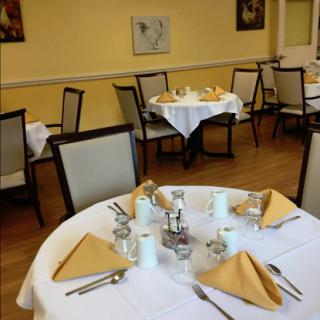A well-set dining area featuring neatly arranged tables with yellow napkins and a warm, inviting atmosphere.
