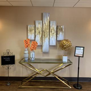 A modern lobby setup featuring a decorative console table with vibrant floral arrangements and abstract wall art.
