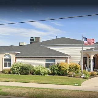 A residential building with a neatly maintained lawn and an American flag flying at the entrance.