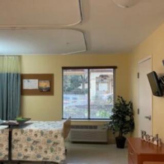 A hospital room with a bed, window, and television on the wall.