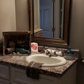 A neatly organized bathroom countertop with a sink, mirror, and decorative items.