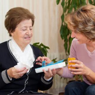 A caregiver assisting an elderly woman with her medication in a home setting.