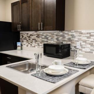 A modern kitchen with a clean countertop featuring two place settings, a microwave, and a stylish mosaic backsplash.