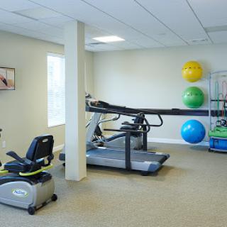 A well-equipped indoor gym featuring a treadmill, exercise bike, and stability balls.