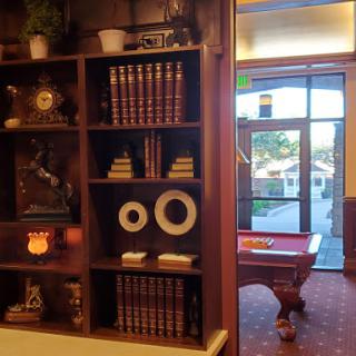 A cozy interior featuring a bookshelf filled with books and decorative items, leading to a room with a pool table.