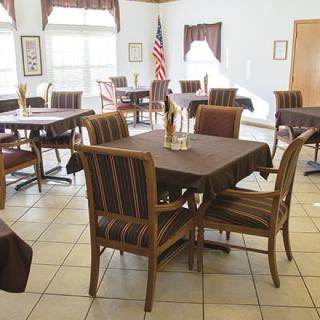 An empty dining area with neatly arranged tables and chairs, featuring a flag in the corner.