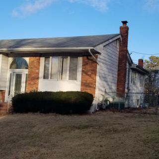 A suburban brick house with a chimney and front yard on a sunny day.