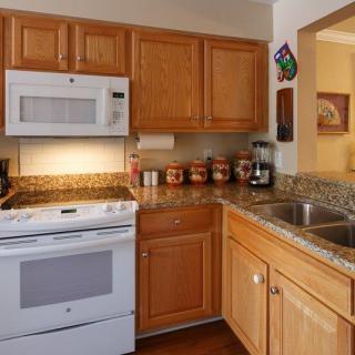 A modern kitchen with wooden cabinets, granite countertops, and white appliances.