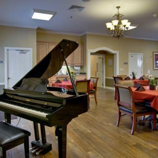 A dining area with a grand piano and elegantly set tables.
