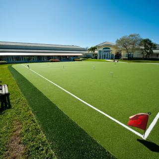A sunny day on an outdoor artificial turf hockey field with a goalpost in view.