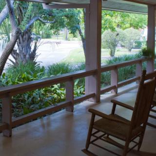 A peaceful porch with rocking chairs overlooking a lush garden.