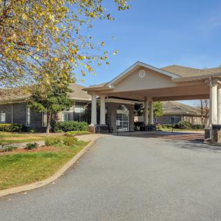 A building with a covered entrance and landscaped surroundings on a clear day.