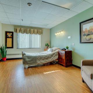 A well-lit hospital room featuring a bed, a couch, and soothing green walls.