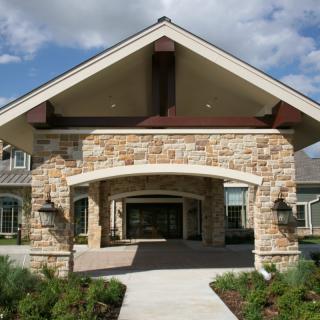 A residential building entrance with a stone facade and landscaped pathway.