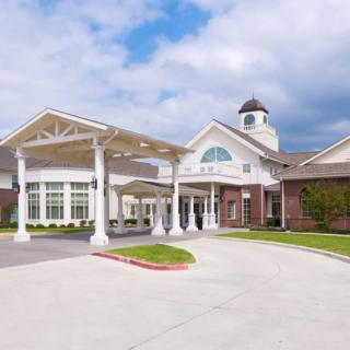 A modern building with a covered entrance and driveway on a cloudy day.