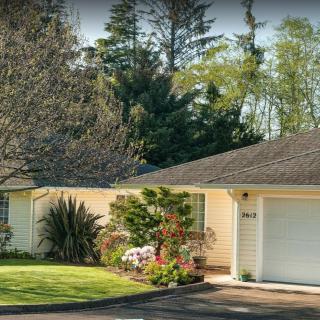 A suburban house with a neatly maintained front yard and surrounding trees.