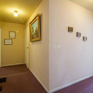 A hallway with artwork on the walls, carpeted flooring, and overhead lighting.