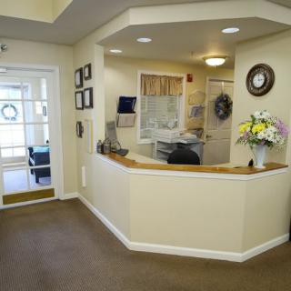 A well-lit reception area featuring a desk adorned with a vase of flowers.