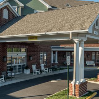 A brick building with a covered entrance and driveway during the daytime.