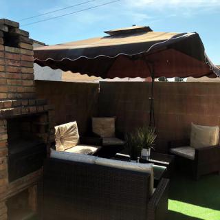 Cozy patio setup with a brick grill and comfortable seating under an umbrella.