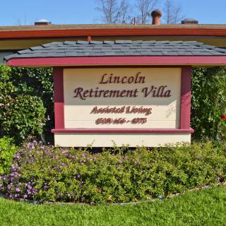 Sign for Lincoln Retirement Villa with contact information, surrounded by greenery.