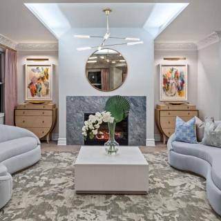 A modern living room with stylish sofas, a central coffee table, decorative artwork, and a fireplace.