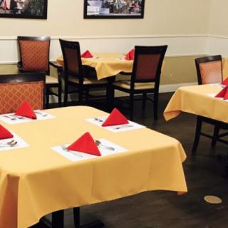 A restaurant dining area with neatly set tables, featuring yellow tablecloths and red napkins.