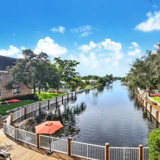 Scenic view of a canal surrounded by buildings and trees under a bright blue sky.