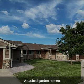 A peaceful suburban neighborhood with attached garden homes under a partly cloudy sky.
