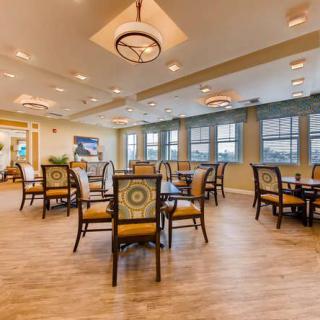 A well-lit dining room with multiple tables and chairs arranged neatly.