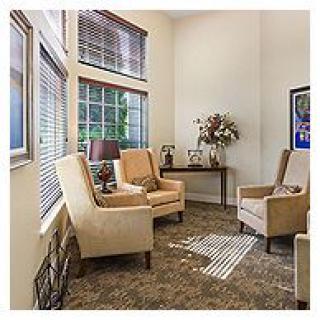 A cozy living room corner with armchairs, a side table, and large windows allowing natural light in.