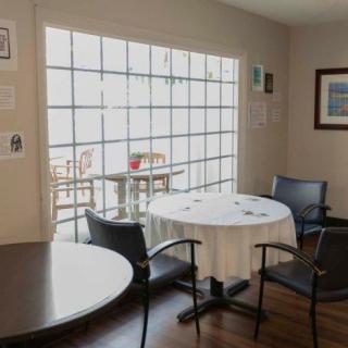 A cozy dining area with round tables and chairs, featuring a large window letting in natural sunlight.