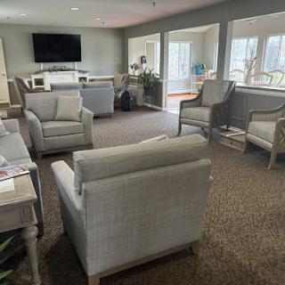 A cozy living room with comfortable seating and a television, bathed in natural light.