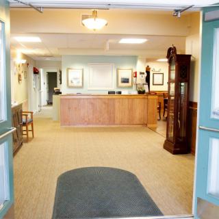 A reception area with a wooden desk and furnishings, leading into a hallway.