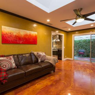 A modern living room with a leather sofa, vibrant artwork, and a skylight illuminating the space.