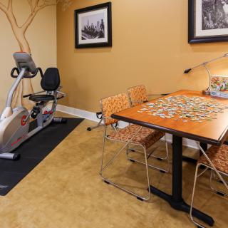 A cozy indoor space featuring an exercise bike and a table set up for a puzzle.