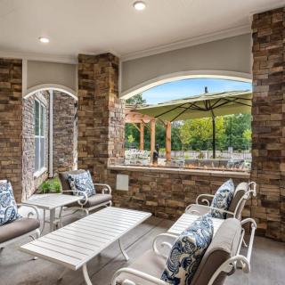 A cozy outdoor patio area with stone walls and comfortable seating overlooking a lush landscape.