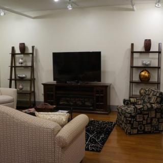 A modern living room with comfortable seating, featuring a large TV and decorative shelving units.