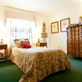 A cozy bedroom with classic decor, featuring a bed, dresser, and vintage-style furnishings.