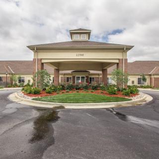 A view of a building entrance with landscaped surroundings and a circular driveway.