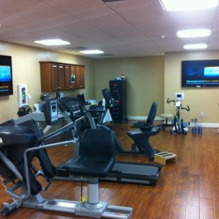 A well-equipped fitness room with various exercise machines and televisions.