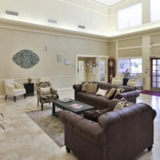 A spacious and elegantly furnished living room with sofas, chairs, a coffee table, and decorative elements.