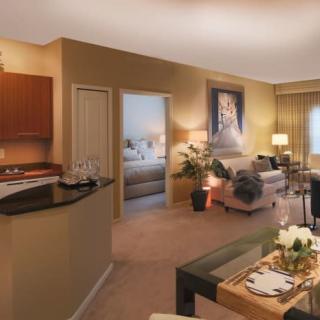 A modern open-concept living room with a kitchen and dining area, featuring stylish furniture and warm lighting.