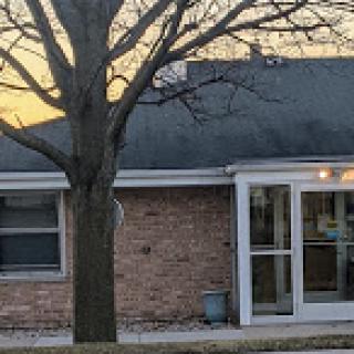 A cozy brick house with a large tree in the front yard during sunset.