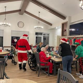 Santa Claus visiting elderly residents during a festive holiday celebration at a nursing home.