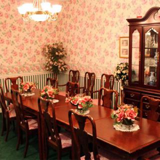 A classic dining room with a long wooden table, matching chairs, elegant chandelier, and floral arrangements.