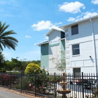 A sunny day view of an apartment building with surrounding palm trees and landscaping.