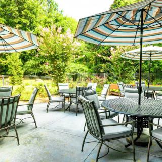 A serene patio with tables, chairs, and umbrellas set amidst lush greenery.